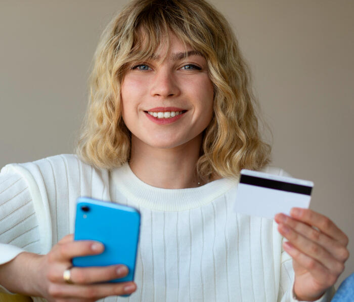 Person funding their Google Ads Campaign. They have their cell phone on one hand and credit card in the other.